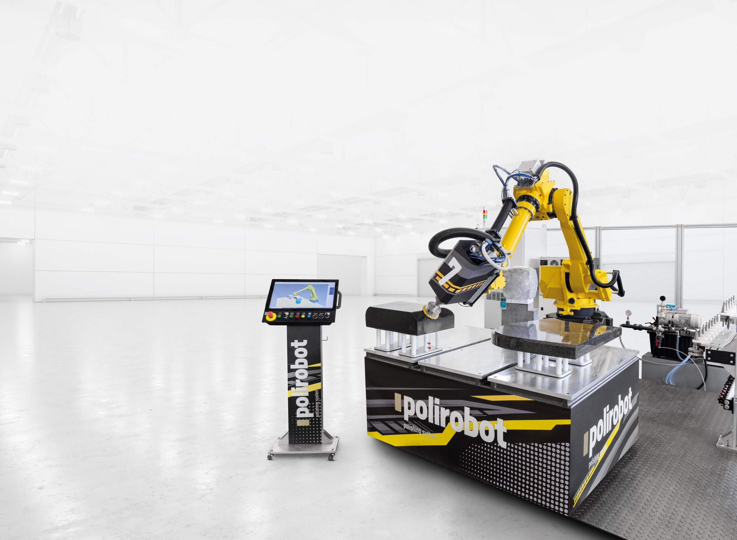 Um braço robótico industrial amarelo opera sobre uma plataforma Polirobot preta e amarela numa fábrica luminosa e limpa, com controlos de ecrã tátil nas proximidades.